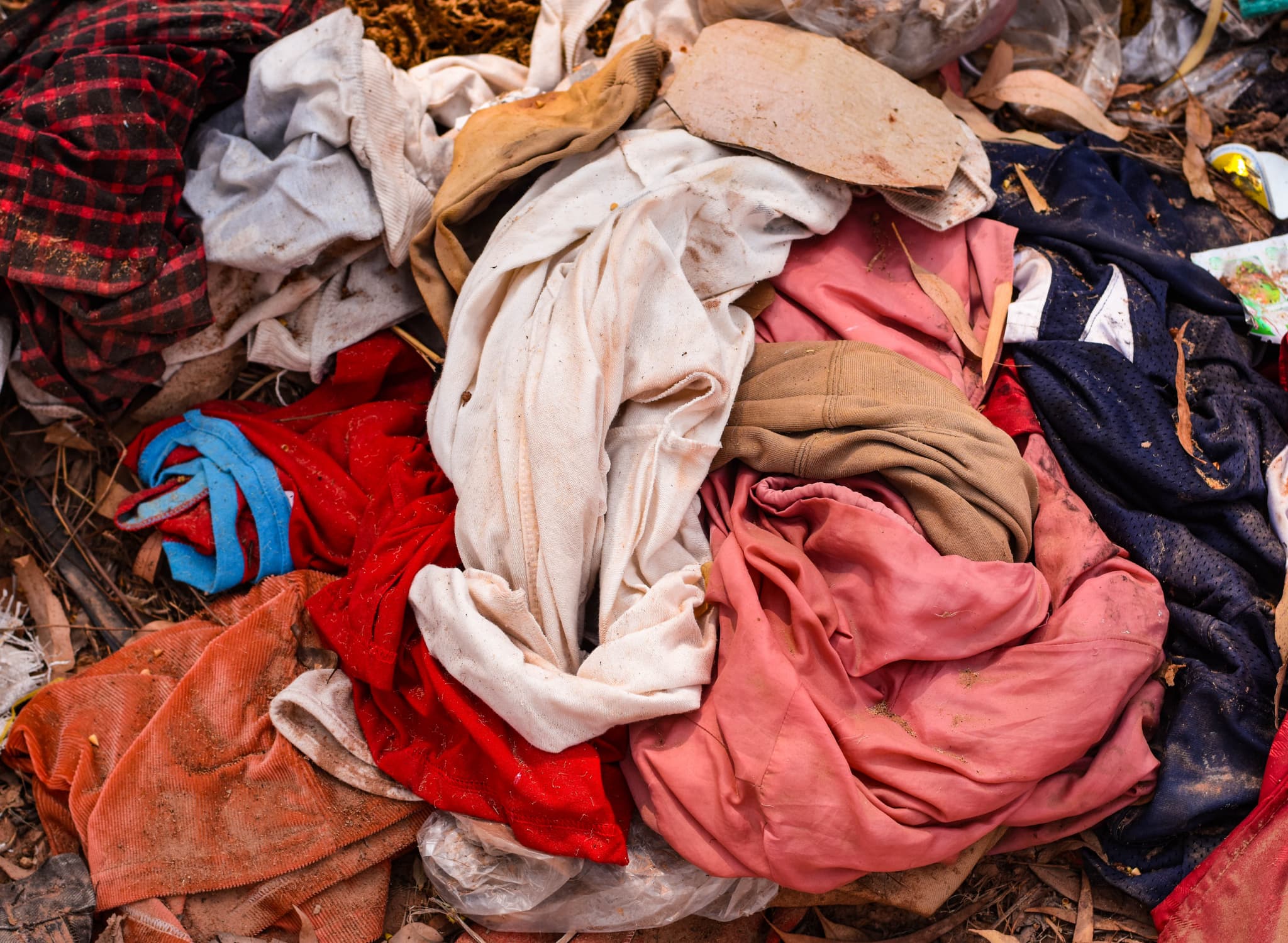 A pile of discarded clothing in landfill. Fashion Declares a climate, ecological and social emergency